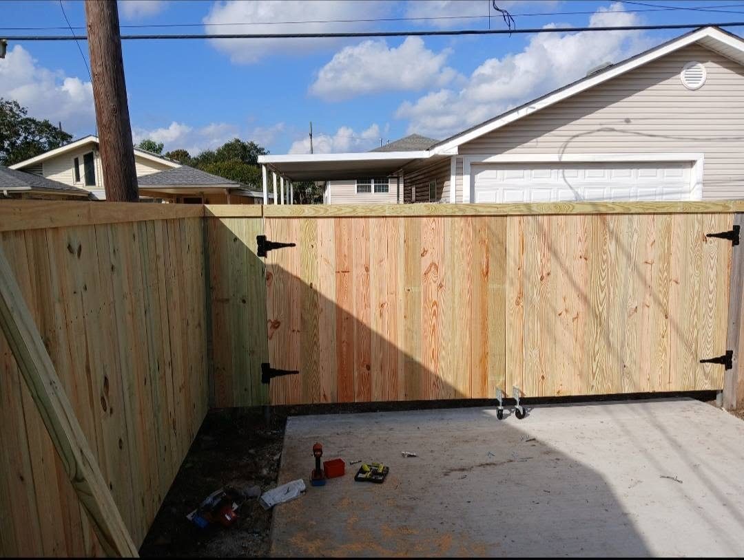 Pressure-treated privacy fence with a rolling gate on a track across a driveway