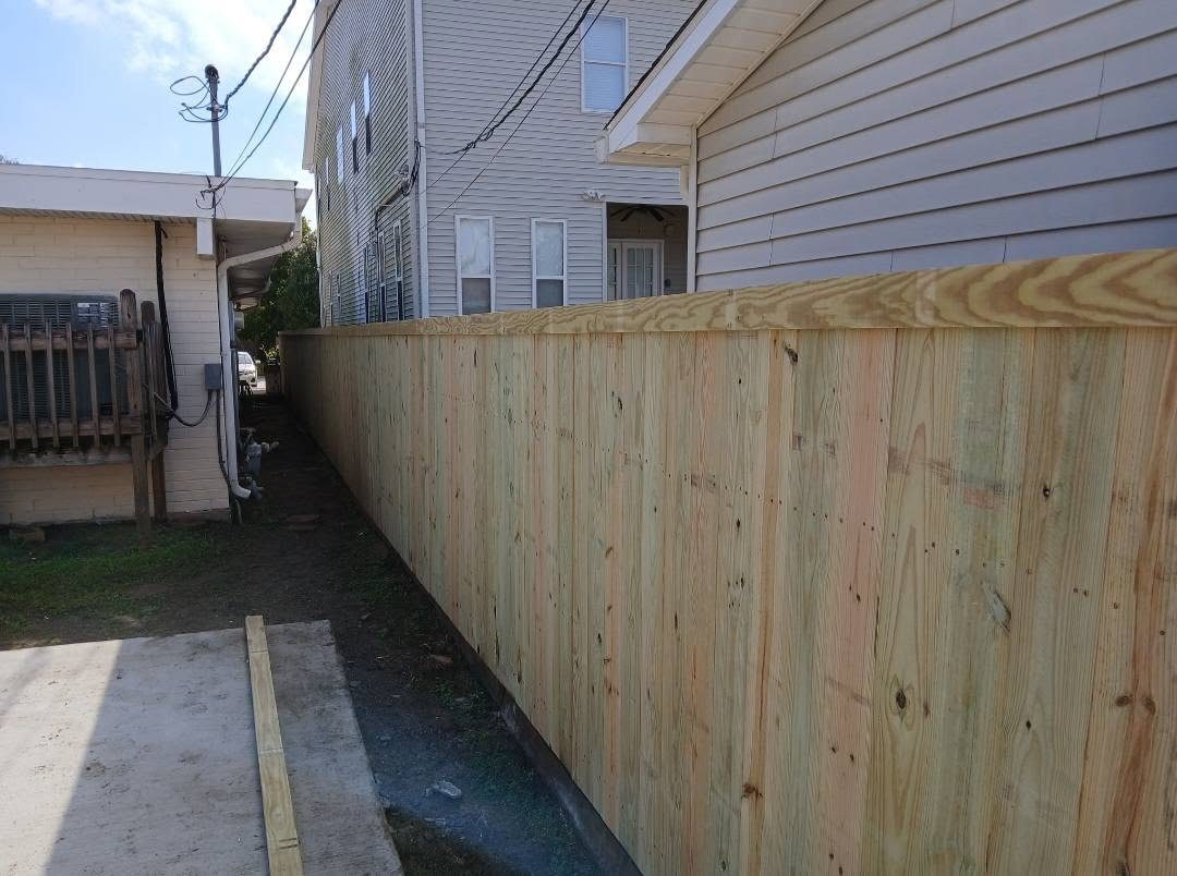 Pressure-treated privacy fence installed along a side yard with a capped top rail